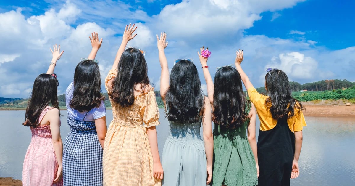 Group of young women outdoors raising hands, enjoying social and outdoor hobbies tailored for black women in their 20s.