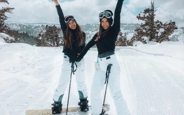 Two women snowboarding in snowy mountains showcasing outdoor hobbies for women in their 20s