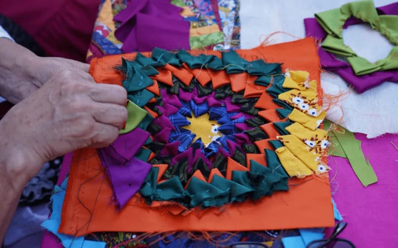 Woman in her 30s engaged in quilting with colorful fabrics, a perfect hobby for women in their 30s with kids or late 30s.