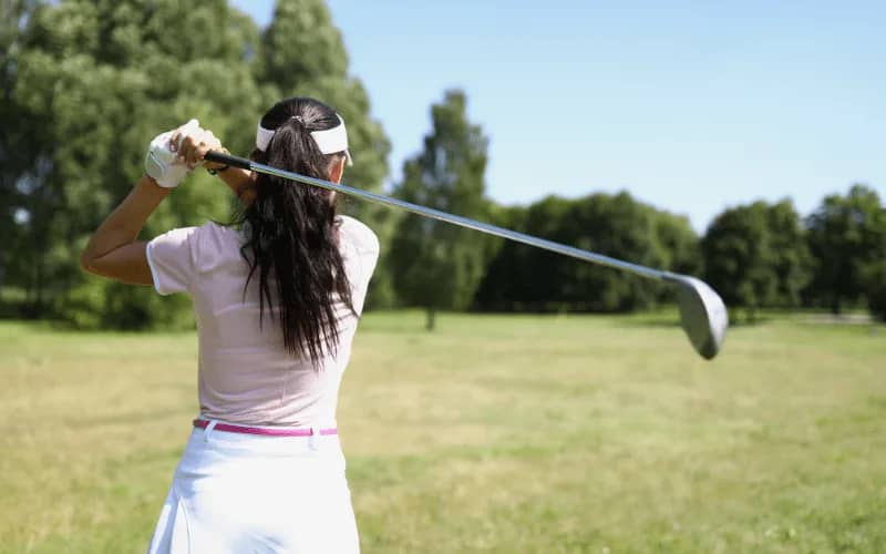 Woman in her 30s playing golf outdoors, an active hobby and leisure activity suitable for women in their late 30s and twenties.