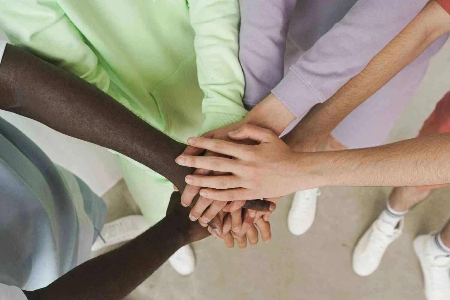 A diverse group of hands stacked on top of each other, signifying a sense of teamwork and friendship.